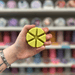 Pear and Freesia wax melt segments held in hand with colourful wax melt display in the background