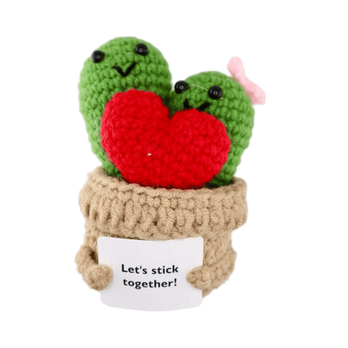 Crochet cactus couple in a yarn plant pot holding a red heart and a Let’s stick together message card on white background