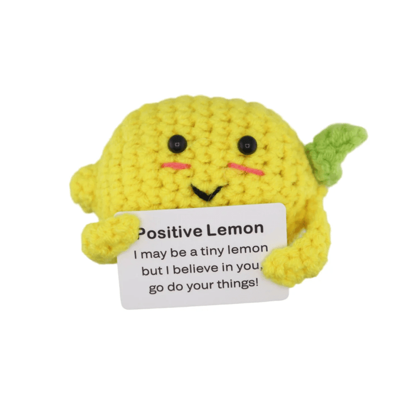 Bright yellow crochet lemon decoration holding a motivational message card on white background