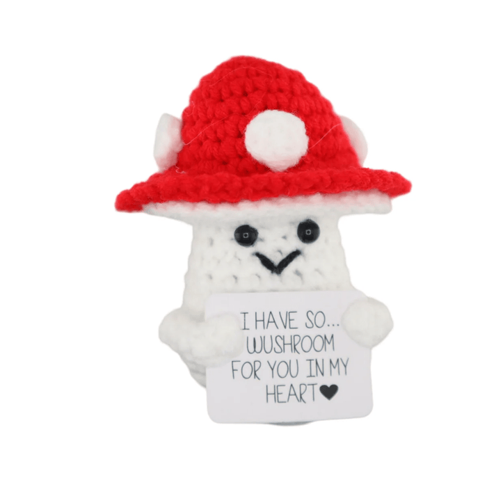 Cute crochet white mushroom with red hat holding a small love message card on white background