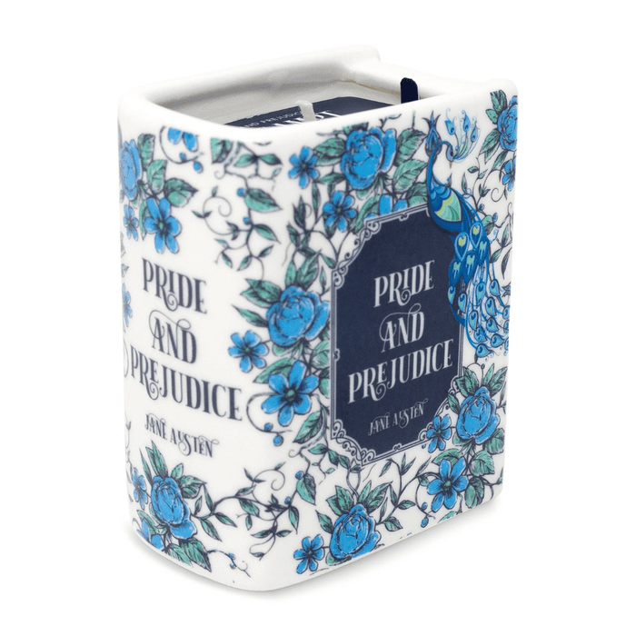 Lit Pride and Prejudice book shaped candle styled on a vintage book with pearls and decorative accessories.