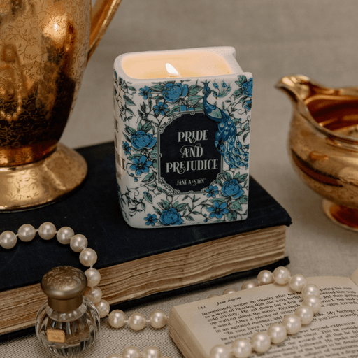 Lit Pride and Prejudice book shaped candle styled on a vintage book with pearls and decorative accessories.