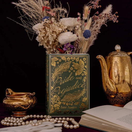 Pride and Prejudice book vase styled with dried flowers beside vintage gold teaware.