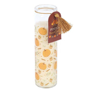 Front view of tall glass pumpkin prayer candle with tassel tag on white background.
