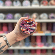 Rainbow Cookie wax melt pot held in hand with colourful wax melt display in the background