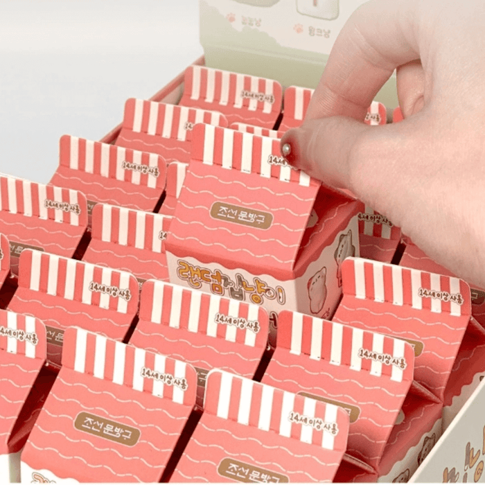 Hand picking a Random Cozy Cat milk-carton blind box from the display tray