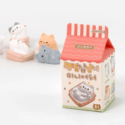 Random Cozy Cat milk-carton style blind box packaging on a white background with figures behind