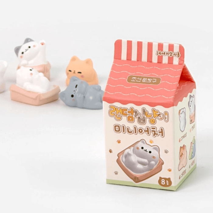 Random Cozy Cat milk-carton style blind box packaging on a white background with figures behind