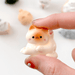 Miniature cosy cat figure held in hand showing the small size and pastel finish