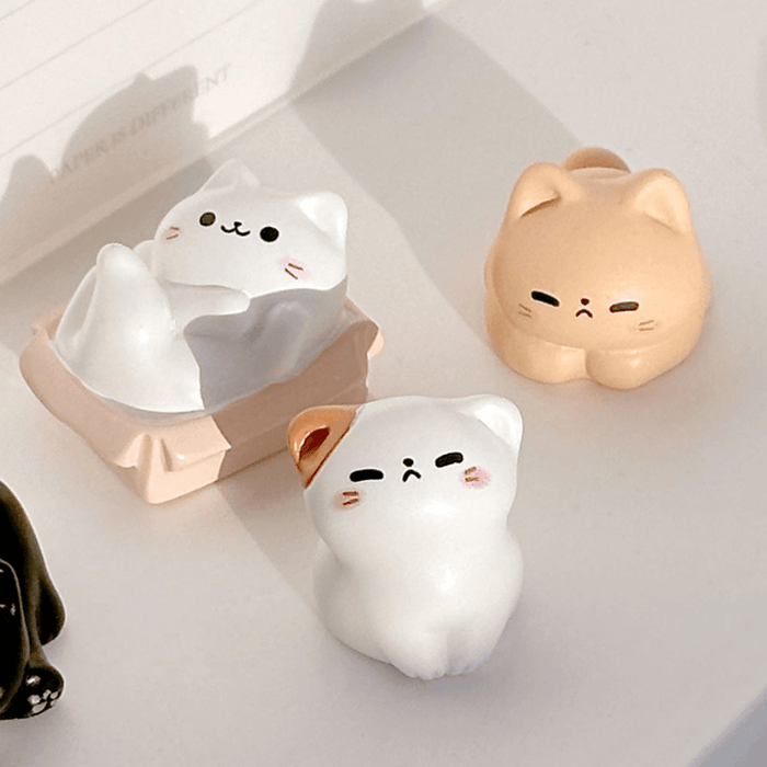 Close-up of three cosy cat miniature figures in soft lighting on a tabletop