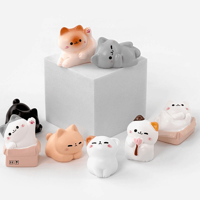 Assorted cosy cat miniature figures posed together around a display block