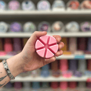 Raspberry Daiquiri wax melt segments held in hand with colourful wax melt display in the background