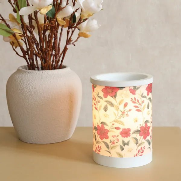 Red floral electric wax melt burner lit in a styled setting, showing the floral pattern illuminated.