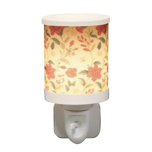 Red floral plug in wax melt burner switched on, glowing warmly through the floral design.