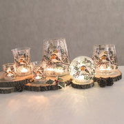 Assorted crackle glass robin tealight holders glowing on wood slices

