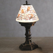 Lifestyle view of LED robin water spinner lamp glowing on a table, robins and berries shade.