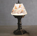 Lifestyle view of LED robin water spinner lamp glowing on a table, robins and berries shade.