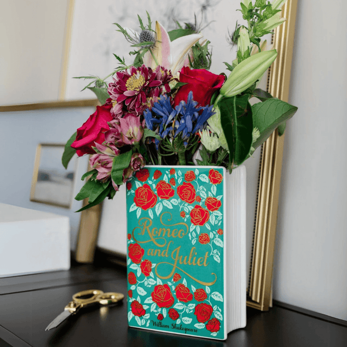 Romeo and Juliet ceramic book vase filled with flowers on a dressing table