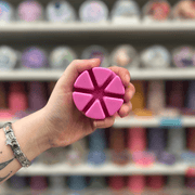 Rose Jam wax melt segments held in hand with colourful wax melt display in the background
