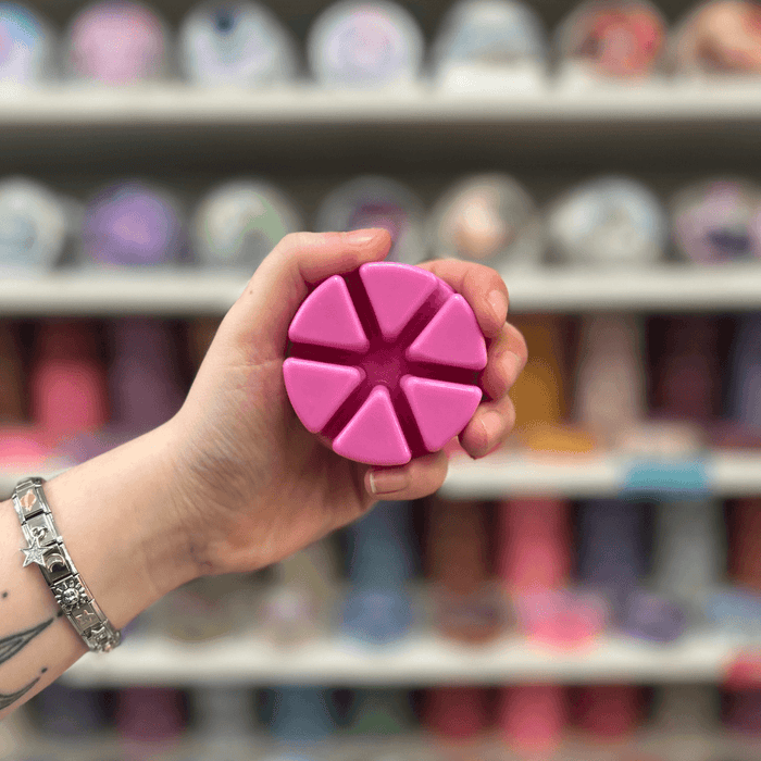 Rose Jam wax melt segments held in hand with colourful wax melt display in the background