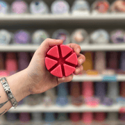 Rouge wax melt segments held in hand with colourful wax melt display in the background