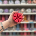 Rouge wax melt segments held in hand with colourful wax melt display in the background