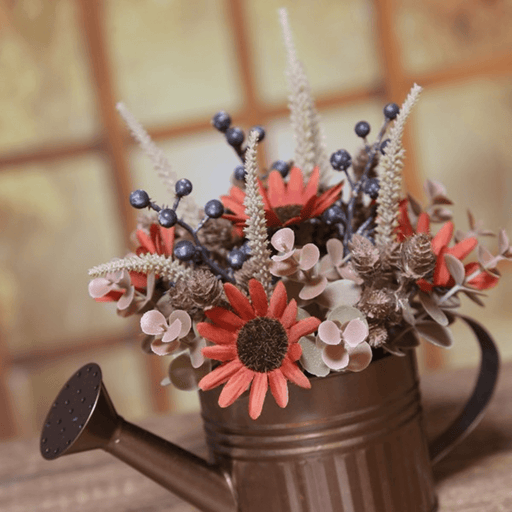 Lifestyle close-up of red and cream autumn flowers and berries arranged in a copper watering can.
