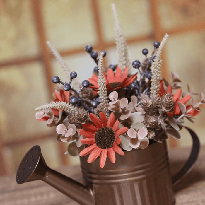 Lifestyle close-up of red and cream autumn flowers and berries arranged in a copper watering can.