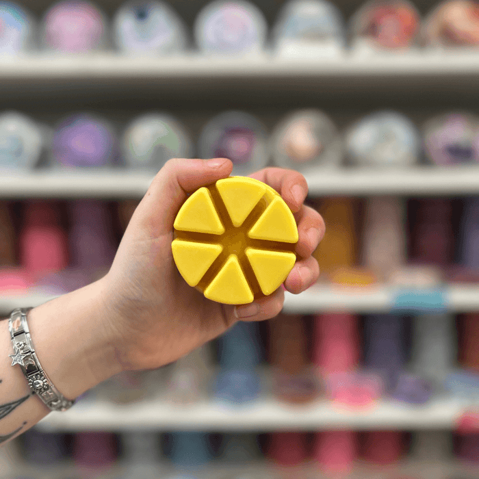 Sandalwood and Black Pepper wax melt segments held in hand with colourful wax melt display in the background
