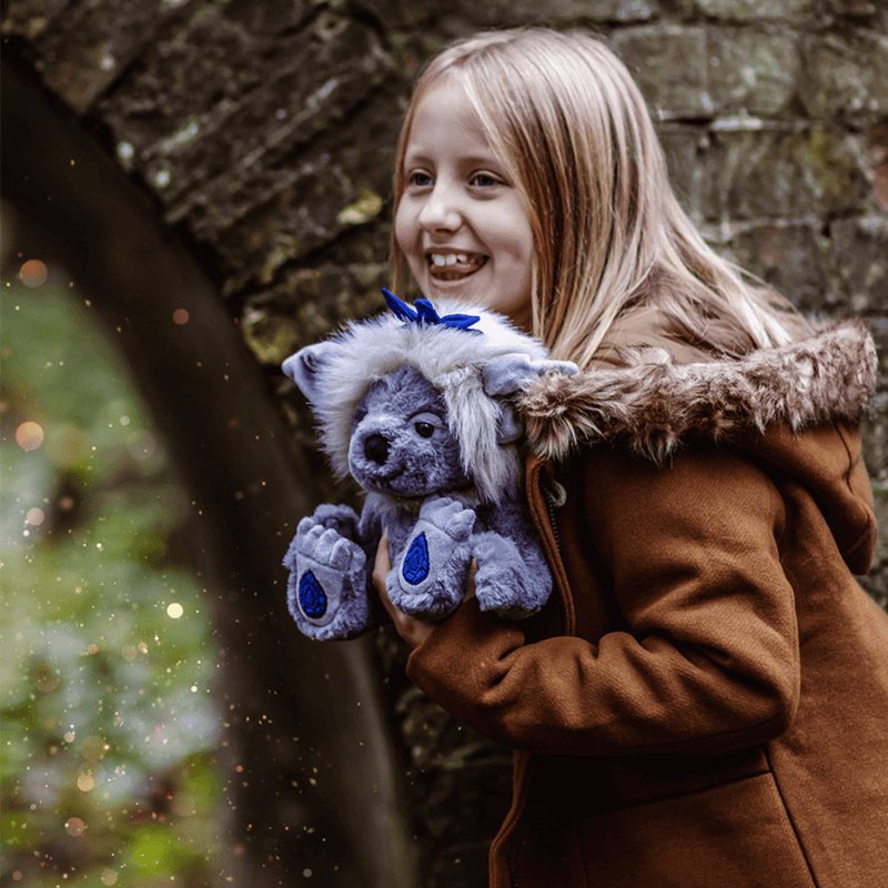 Child holding Sapphire Sue crystal troll plush by Charlie Bears outdoors, cosy lifestyle photo