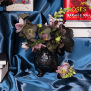 ACOTAR Cauldron vase filled with flowers beside A Court of Thorns and Roses books