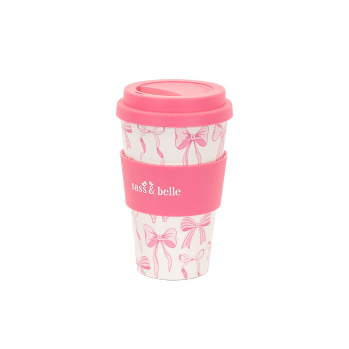 Pink Sass & Belle bow travel coffee cup with lid and grip sleeve on a white background