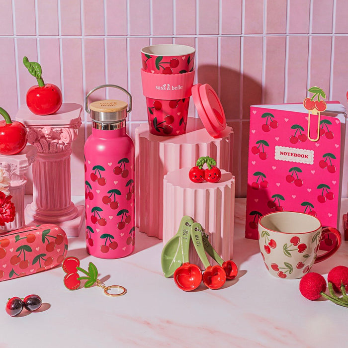 Cherry travel coffee cup shown with matching Sass & Belle cherry accessories in a pink lifestyle scene