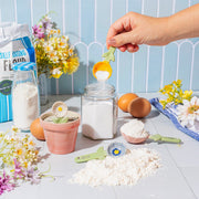 Person using Sass & Belle yellow flower measuring spoon while baking