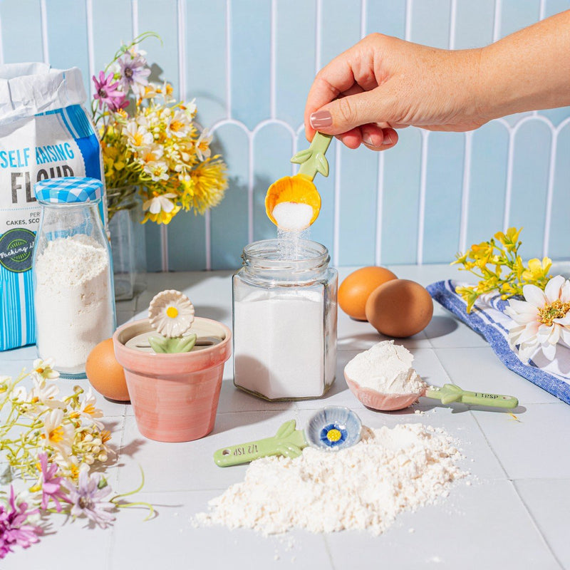 Person using Sass & Belle yellow flower measuring spoon while baking