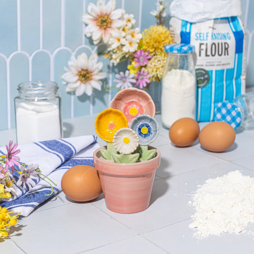 Sass & Belle flower measuring spoons with flour and eggs on a tiled kitchen counter