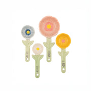 Four Sass & Belle flower-shaped measuring spoons in pastel colours laid out flat
