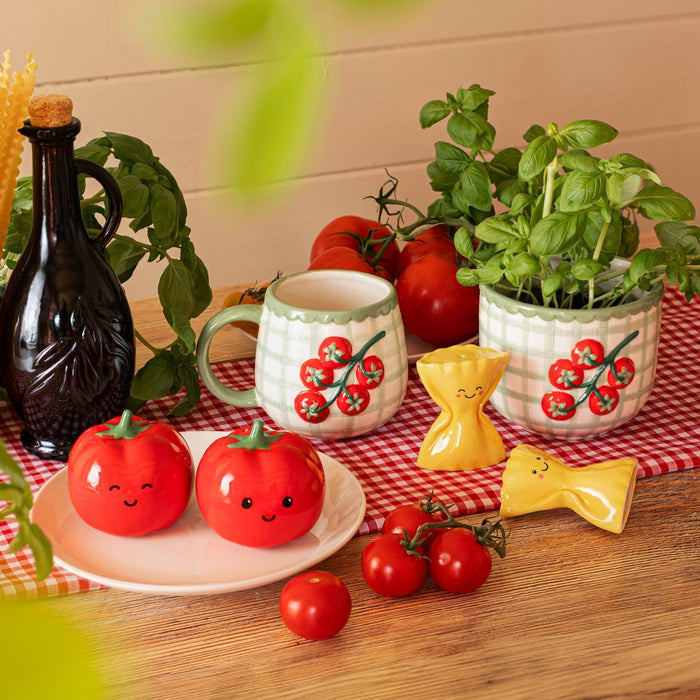 Farfalle pasta salt and pepper shakers with tomato-themed kitchenware and basil plants