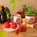 Farfalle pasta salt and pepper shakers with tomato-themed kitchenware and basil plants