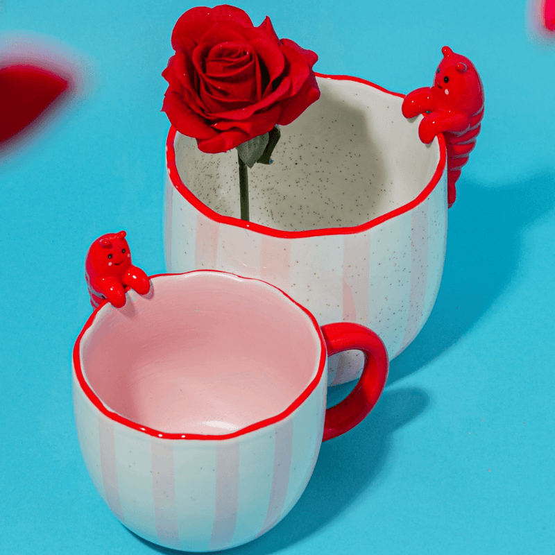 Sass and Belle Peeking Lobster mug styled with a red rose, showing the playful lobster detail and pink striped design