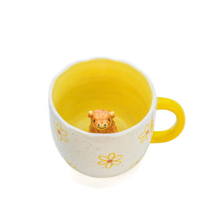 Angled view into Sass & Belle Highland Cow Daisy Mug with sunny yellow glaze and cow figurine waiting inside
