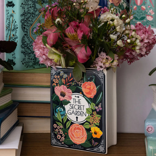 Floral Secret Garden ceramic book vase styled on a shelf with blooms.