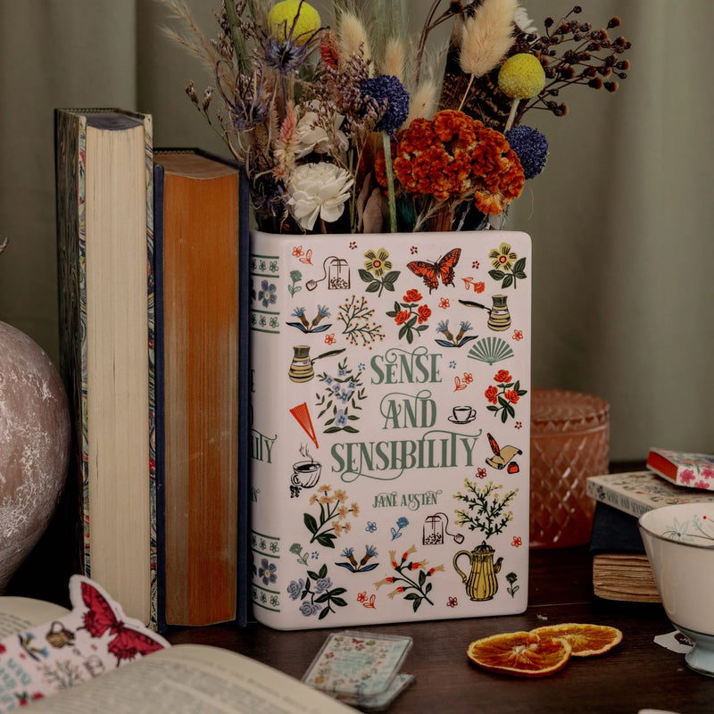 Sense and Sensibility book vase styled with dried flowers on a cosy desk beside classic books.