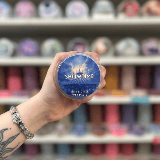 Showtime wax melt pot held in hand with colourful wax melt display in the background