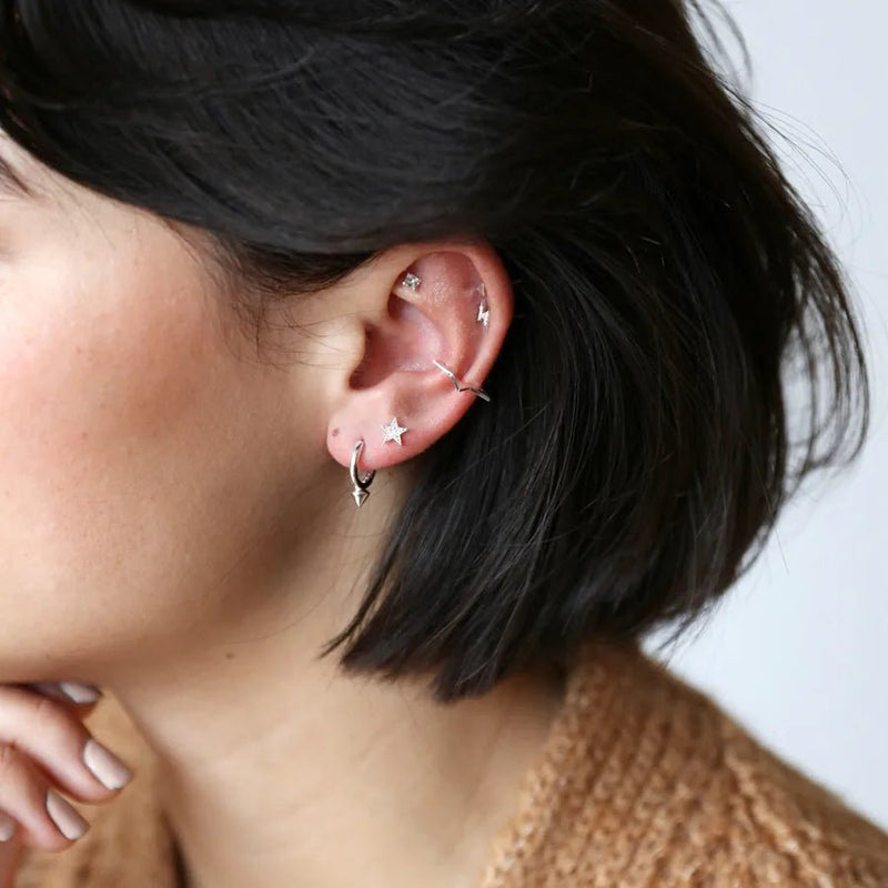 Silver moon and star crystal stud earrings worn in a curated ear stack