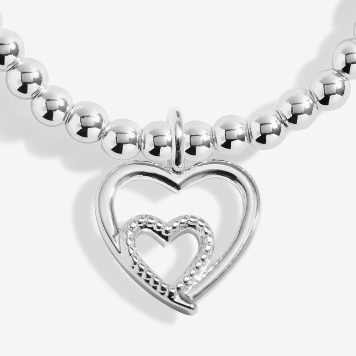 Close-up of Joma Jewellery open double heart charm with textured inner heart on a silver-plated beaded Bracelet.