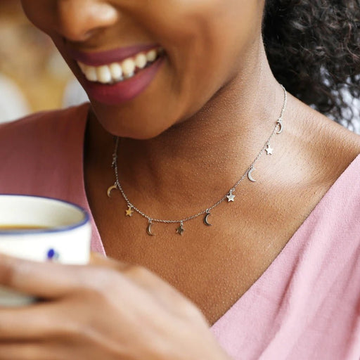 Model wearing a dainty silver necklace with alternating moon and star charms for a subtle celestial look.