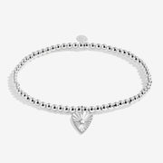 “Flat‑lay of silver‑plated beaded bracelet with sunburst heart charm”

