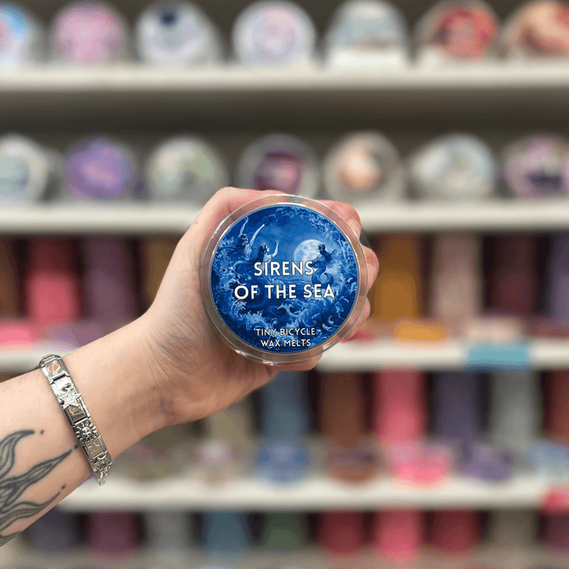 Sirens of the Sea wax melt pot held in hand with colourful wax melt display in the background