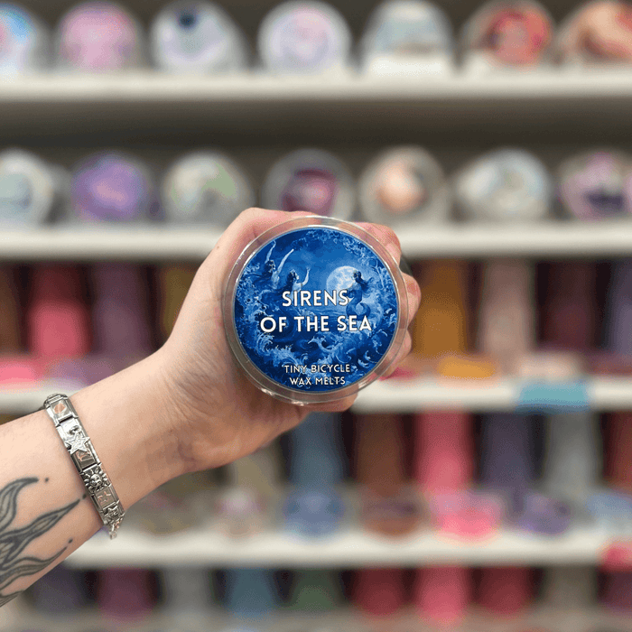 Sirens of the Sea wax melt pot held in hand with colourful wax melt display in the background